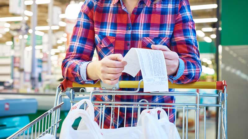 Grande plano de mulher a ver o recibo das suas compras de supermercado - alusão ao fim do IVA Zero